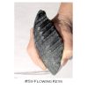 A hand holding a piece of black stone.