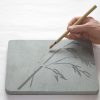 A person is drawing on a stone with a pencil.