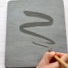 A person writing on a slate with a pencil.