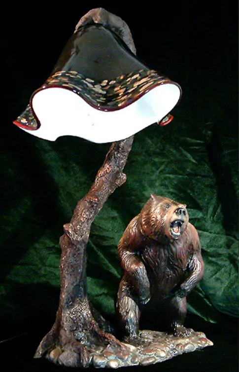 A bear statue sitting on top of a tree branch.